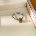 Détail d'une bague minimaliste en argent avec un zircon vert dans un écrin élégant - Vert olive