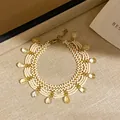 Élégant bracelet en perles crème vintage avec breloques en cristal jaune et finition dorée - Bracelet-Doré Beige