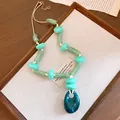 Bohemian style acrylic necklace featuring an oval pendant and mixed green beads. - Green