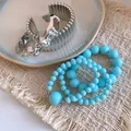 Nahaufnahme der silbernen Manschette und des blauen Acrylperlen-Armbandsets - Mehrteiliges Set / Silber-Himmelblau