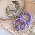 Vue détaillée de bracelets en perles acryliques mauves et manchettes en métal argenté. - Argent-Violet