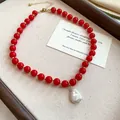 Detailed shot of a red acrylic bead necklace with a white baroque pearl pendant - Red