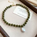 Detail view of olive green beaded necklace with a large white baroque pearl pendant - Olive Green