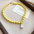 Close-up of a vibrant yellow acrylic beaded necklace with a unique Baroque pearl pendant. - Yellow