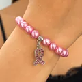Vue rapprochée d'un pendentif ruban rose contre le cancer sur un bracelet de perles roses - Bracelet Pendentif Strass Ruban Rose (S474) / Or