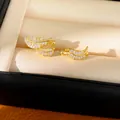 Detail view of gold leaf ear cuffs set with sparkling zircon stones in a jewelry box. - Feather/Leaf Style / Pair Pack / Gold