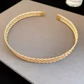 Primo piano di un girocollo in metallo dorato con intricata trama a rete intrecciata - Girocollo increspato / Oro