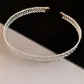 Dettaglio macro del girocollo in metallo intrecciato argento con un elegante motivo a croce - Girocollo increspato / Argento
