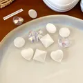 Close-up of pearlescent white and holographic resin shoe charms in various cute shapes. - Green/White