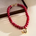 Macro view of a magenta acrylic marbled bead necklace with a polished gold heart pendant - Necklace-Red