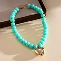Detail showing marbled turquoise beads and large shiny gold heart pendant on necklace - Necklace-Cyan