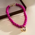 Detail view of magenta acrylic beaded necklace with a polished gold heart pendant. - Necklace-Purple