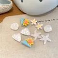 Detail of summer-themed shoe charms featuring iridescent shells and starfish designs - 10 Pieces Pack / White-Blue-Yellow