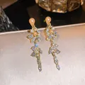 Nahaufnahme eleganter goldfarbener Quastenohrringe mit Zirkonia und Champagnerperlen - Federquasten Ohrhänger (HE34585) / Goldbraun