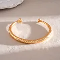 Gedetailleerde close-up van een goudkleurige armband met geometrische textuur op steen - Ruitpatroon Stijl / Goud