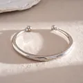 Macro-weergave van een gepolijste zilveren C-vormige open armband met bolvormige eind - Gladde Stijl / Zilver