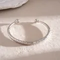 Gedetailleerde weergave van een zilveren C-vormige armband met geometrische texturen - Schuine Stijl / Zilver