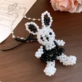 Détail exquis d'un collier avec pendentif lapin en perles noires et blanches fait main et un nœud - Lapin / Blanc-Noir