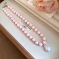 Detailed view of pink acrylic bead necklace with large baroque pearl pendant. - Pink
