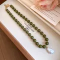 Detail view of a vintage green bead necklace with a baroque pearl pendant in a box. - Olive Green