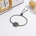 Close-up detail of adjustable silver stainless steel bracelet with engraved charm - Silver