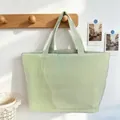 Detail of a green striped tote bag hanging on a minimalist wooden wall hook - Bean Green
