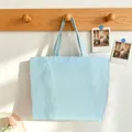 Detail of a blue and white striped tote bag hanging on a wooden hook in a cozy setting. - Mint Green