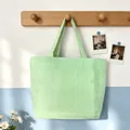 Detailed view of a green and white striped seersucker tote bag hanging on a wooden hook - Green