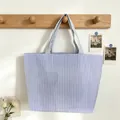 Detailed view of a blue and white striped tote bag hanging on a wooden wall rack - Dark Blue