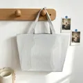 Detail of a gray and white striped tote bag hanging on a wooden wall hook. - Gray
