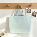 Detailed view of a light blue and white striped tote bag hanging on a wooden rack - Lake Blue