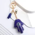 Vue détaillée du porte-clés main de Hamsa bleu orné de strass brillants et œil bleu. - Bleu