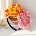 Nahaufnahme von 12cm großen künstlichen Kamelienblüten auf einem schwarzen Stirnband - Verlauf Orange Und Hellrosa (FG215-4)