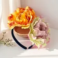 Detailansicht eines Haarreifens mit großen orangefarbenen und rosa Kamelienblüten. - Orange Gelb Und Rosa Grün (FG215-1)