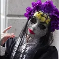 Close-up detail of Day of the Dead mask with purple floral crown and black lace veil - Purple Flowers & Yellow Face