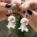 Détail en gros plan de boucles d'oreilles momie blanche tenues à la main pour Halloween - Style Momie Borgne (2)