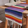 Vibrant woven Mexican rainbow table runner with fringe detail on a rustic wooden table - Mexican Blanket - Purple Tones