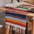 Detailed view of a Mexican rainbow serape table runner with white tassels on a table - Mexican Blanket - Coffee Tones