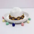 Detail view of a mini white Mexican sombrero hat with colorful pom-poms and gold trim - Headband Style / White Felt Style with Colorful Pompoms (46) / White (46)