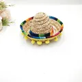 Close-up detail of a mini Mexican straw sombrero with rainbow ribbon and yellow pom-poms - Natural Straw (Style 6) / Diameter 16cm / Straw Hat Yellow Pom-Pom (Style 6)