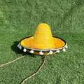 Gele Mexicaanse strooien sombrero met witte pompons en gevlochten band op groen gras - Diameter 33-35cm / Met Witte Pompons / Geel