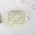 Overhead detail view of a quilted floral mini pouch with flap button and zipper closure - Soft Yellow Small Flowers