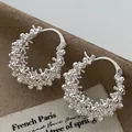 Macro view of silver hollow round basket hoop earrings with intricate textured bubble design. - Ear Buckle / Silver