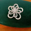 Primo piano di un ciondolo a fiore cavo placcato oro bianco 18k con zirconi lucidi - Spilla / Argento