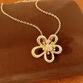 Primo piano di una collana con ciondolo a fiore traforato placcato in oro 18k con zirconi - Collana / Oro