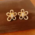 Primo piano di orecchini a lobo a fiore traforato placcati oro con zirconi luminosi. - Stud orecchini / Oro