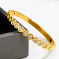 Close-up detail of a gold-plated stainless steel bangle featuring sparkling round crystals - Round Rhinestone Style (42-E-6) / Gold