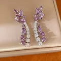 Nahaufnahme eleganter lila Blumenohrringe mit funkelnden Zirkonia-Quasten. - Silber-Lila