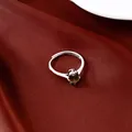 Zoom sur une élégante bague ovale en zircon vert avec finition argentée sur satin rouge. - Bleu Paraïba