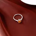 Detailansicht eines silbernen Rings mit einem orangefarbenen Zirkon auf rotem Satin - Gelb
